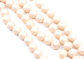 peach colored shimmer acrylic beads arranged in diagonal strands on a white background.