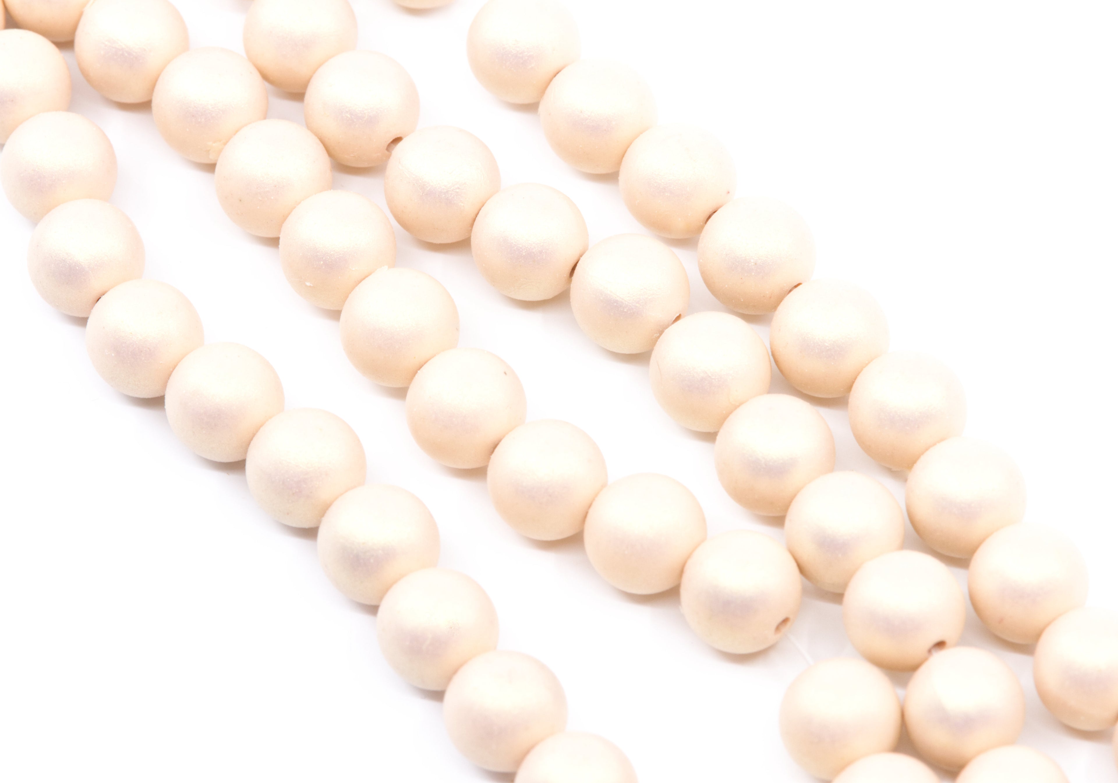 peach colored shimmer acrylic beads arranged in diagonal strands on a white background.