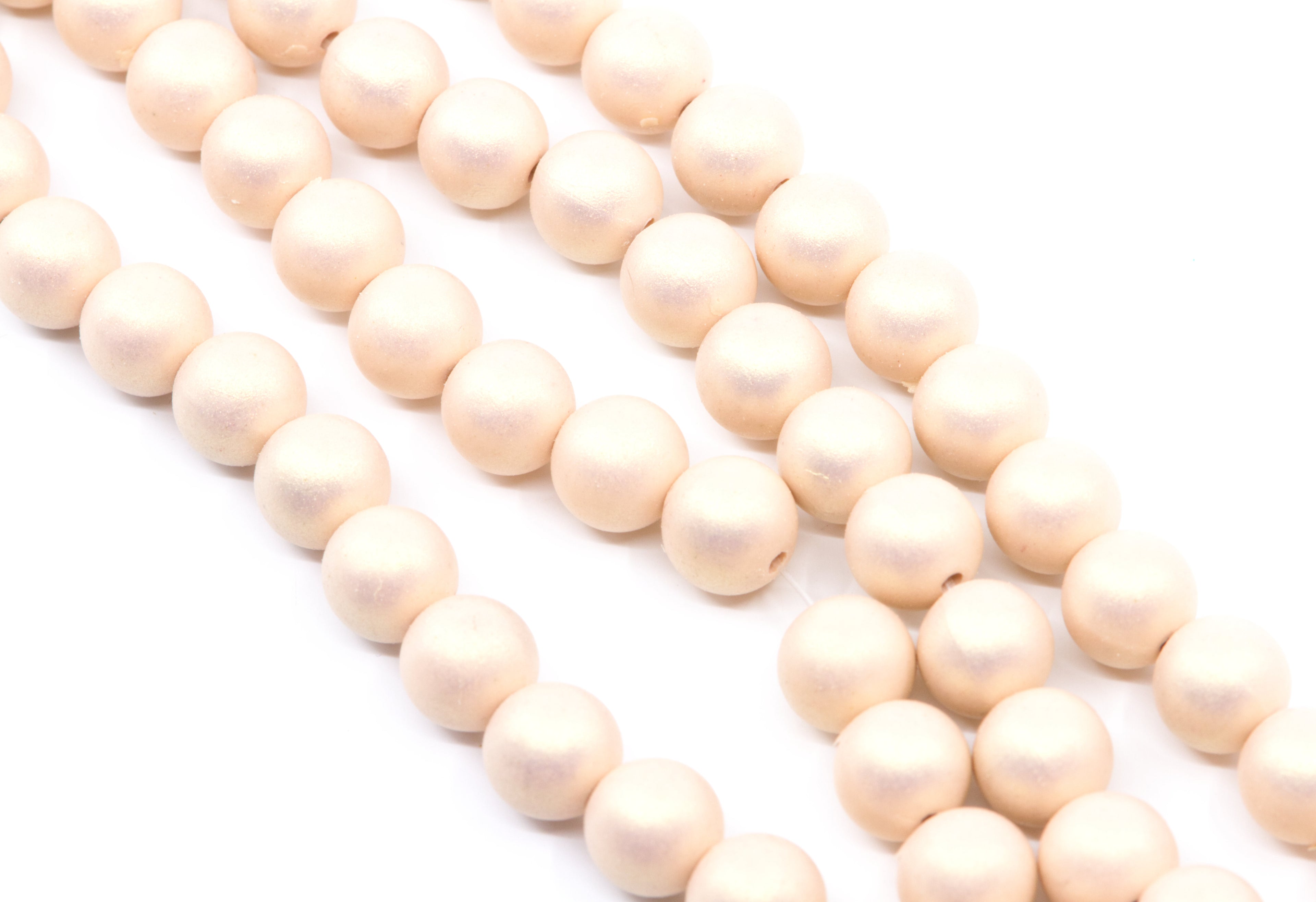peach colored shimmer acrylic beads arranged in diagonal strands on a white background.