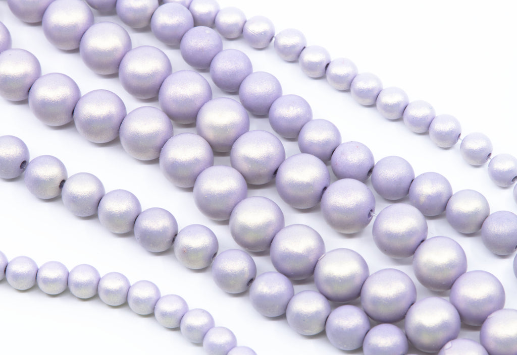 Multiple strands of purple shimmery acrylic beads arranged diagonally on a clean white background.