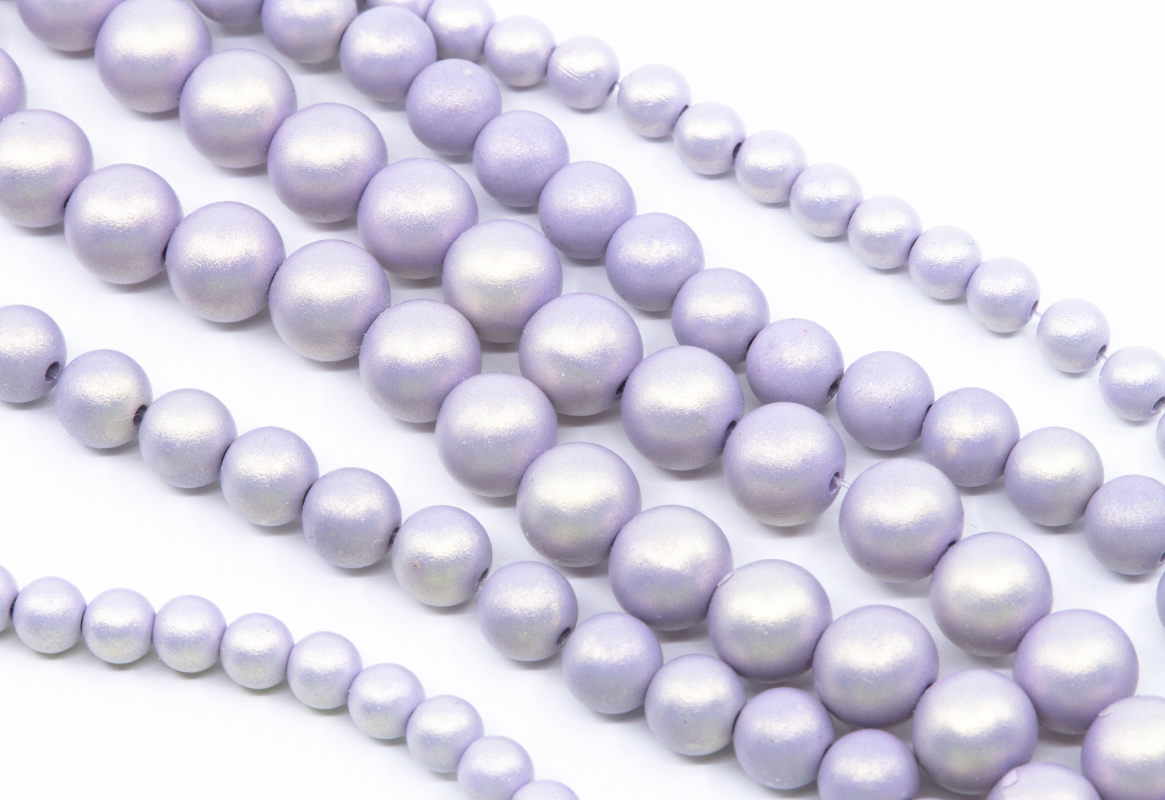 Multiple strands of purple shimmery acrylic beads arranged diagonally on a clean white background.