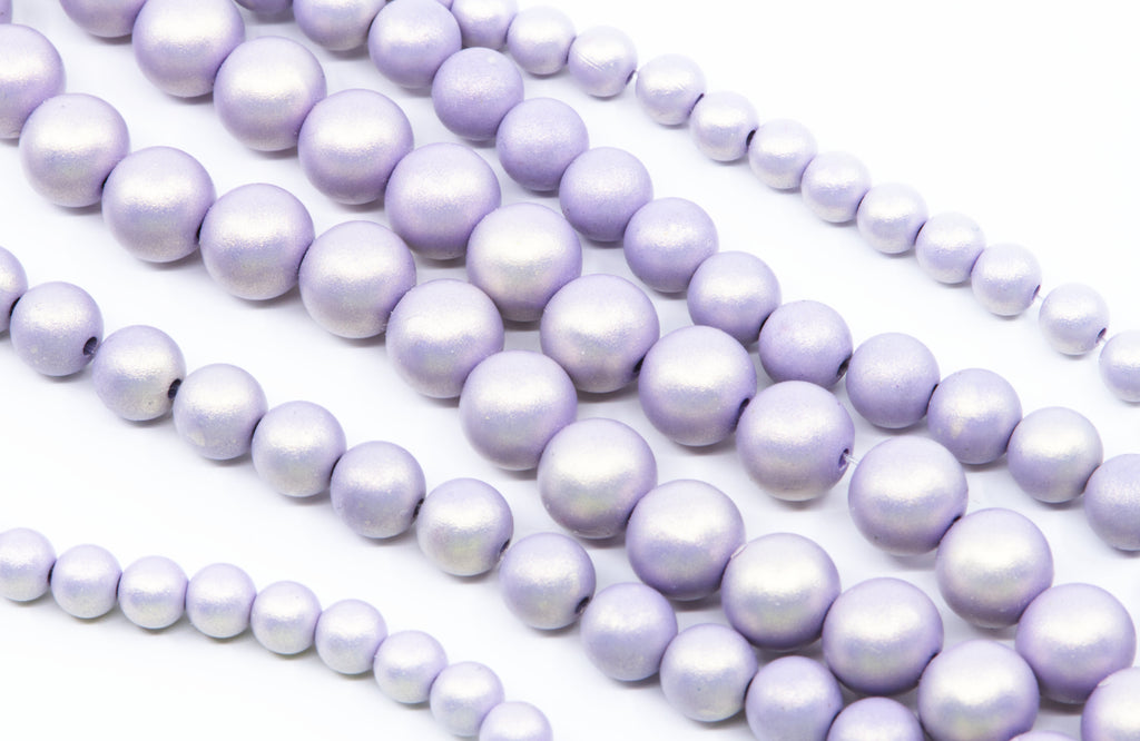 Multiple strands of purple shimmery acrylic beads arranged diagonally on a clean white background.
