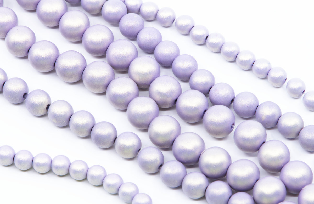 Multiple strands of purple shimmery acrylic beads arranged diagonally on a clean white background.