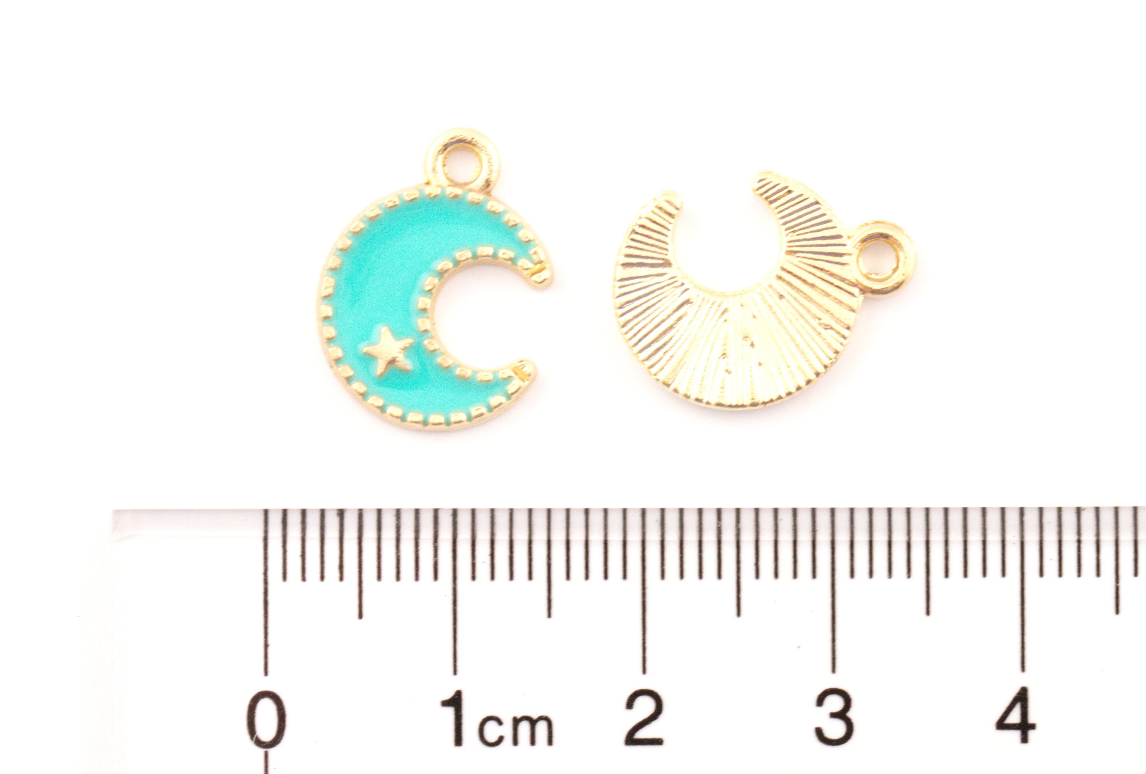 Two small crescent moon jewelry charms shown above a ruler for scale on a white background. 