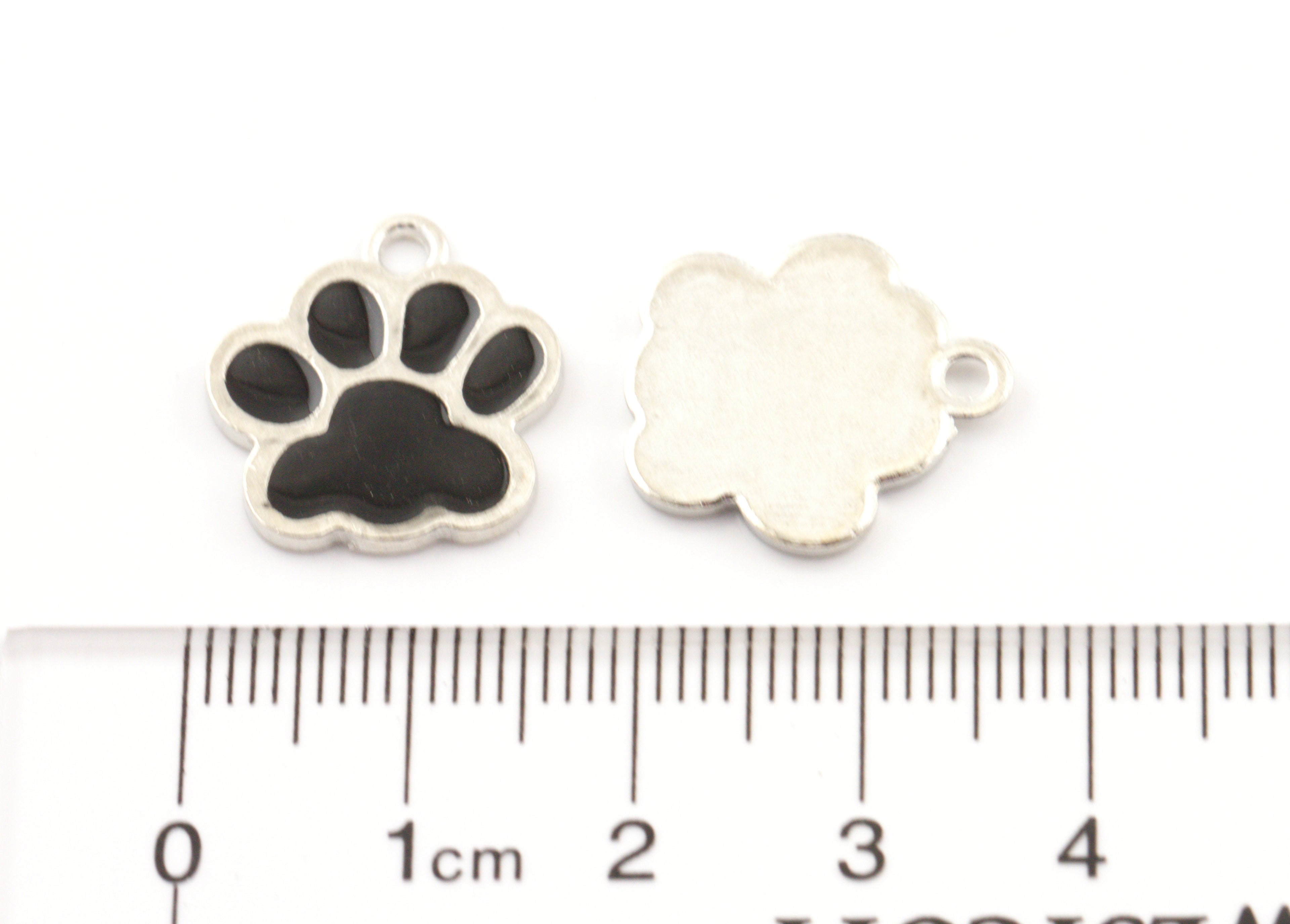 Two small paw-shaped jewelry charms shown on a white background above a ruler for scale. 