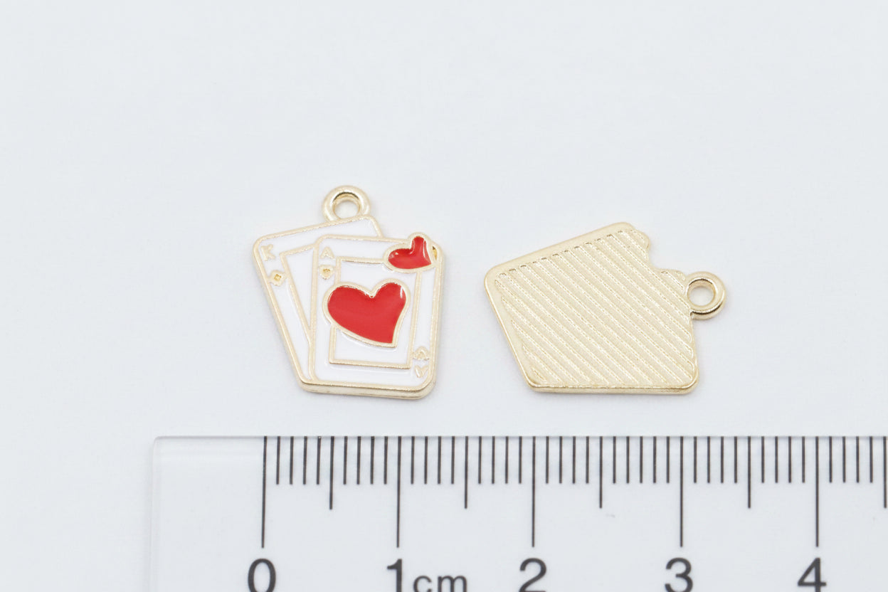 Two small red and white playing card charms shown on a white background with a ruler at the bottom for scale. 