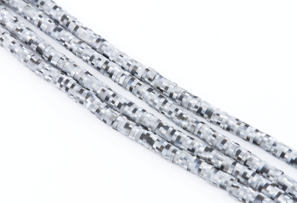 Several strands of polymer clay beads with a black and white pixelated or digital camouflage pattern, arranged diagonally on a plain white background.