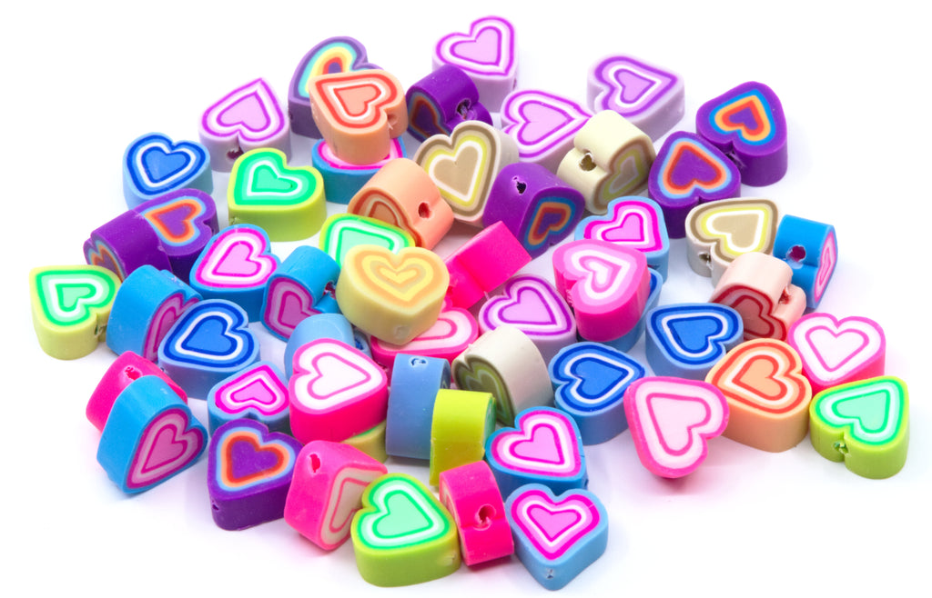 A pile of small heart-shaped polymer clay craft beads in various vibrant colors, including pink, blue, green, purple, orange, and yellow, on a plain white background.