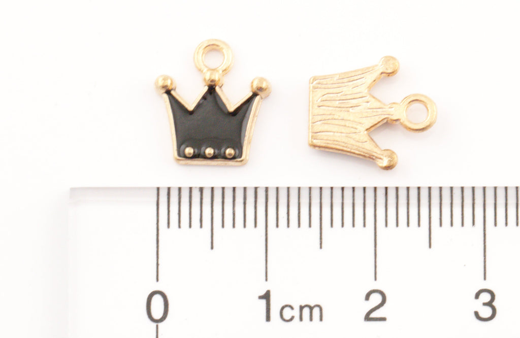 Two small crown-shaped jewelry charms shown above a ruler for scale on a white background. 