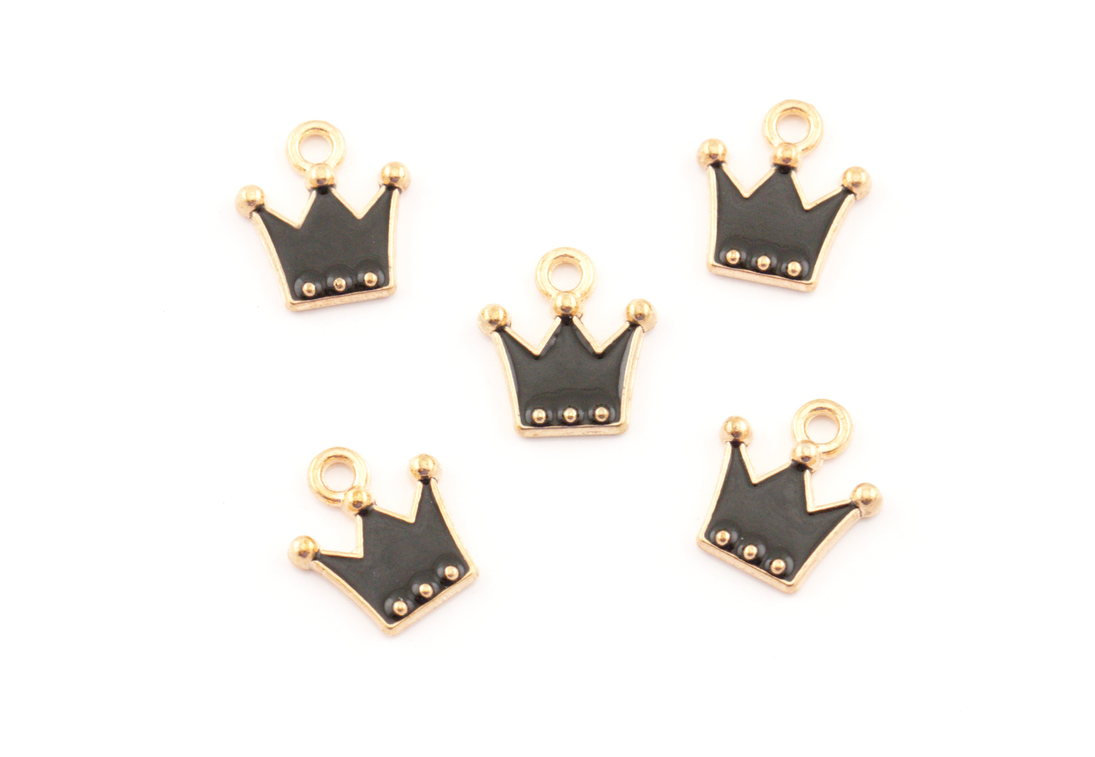 Five small crown-shaped charms with black enamel and gold-tone metal borders, arranged on a plain white background.