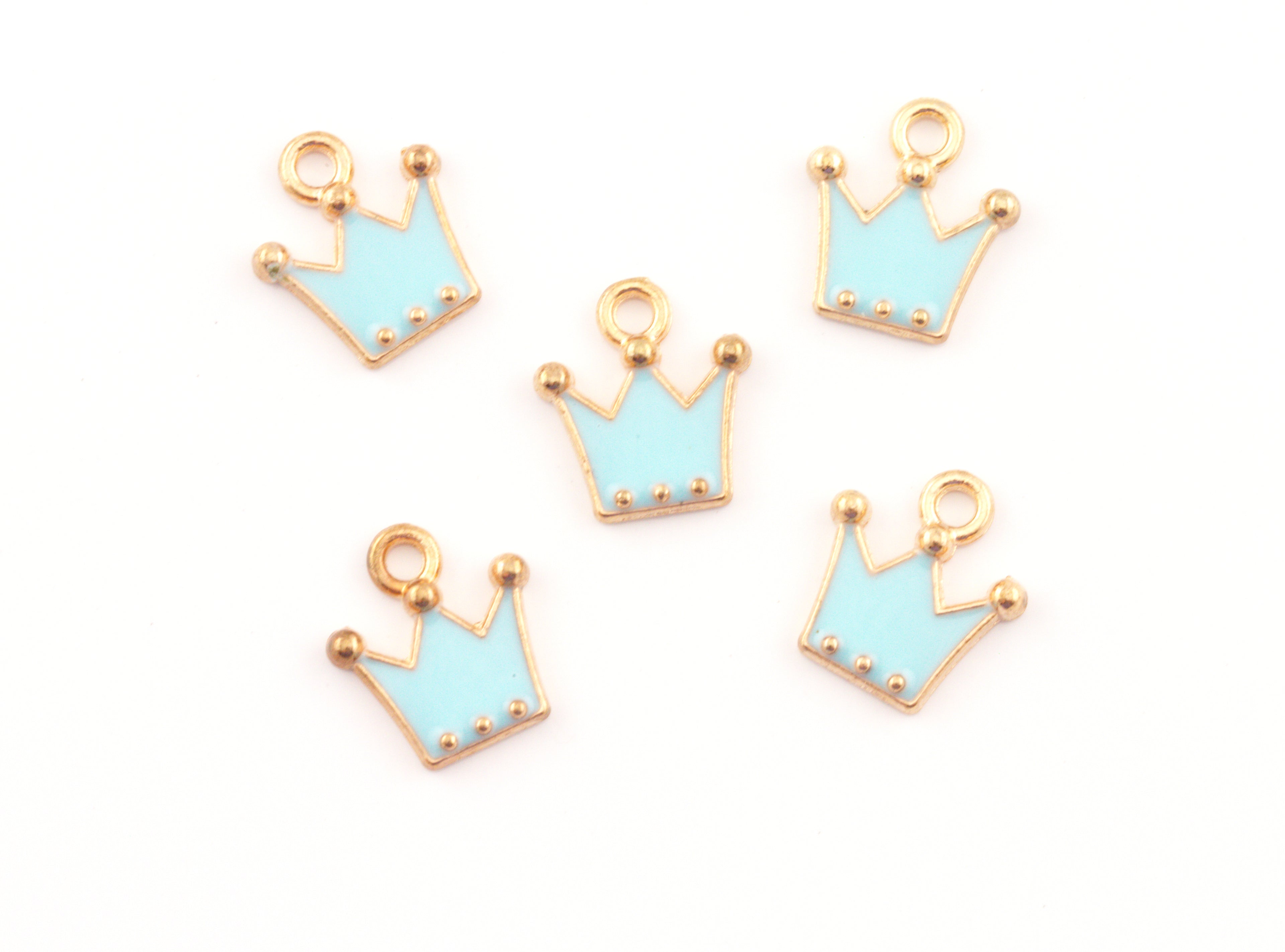 Five small crown-shaped jewelry charms with light blue enamel and gold-tone metal borders, arranged on a plain white background.