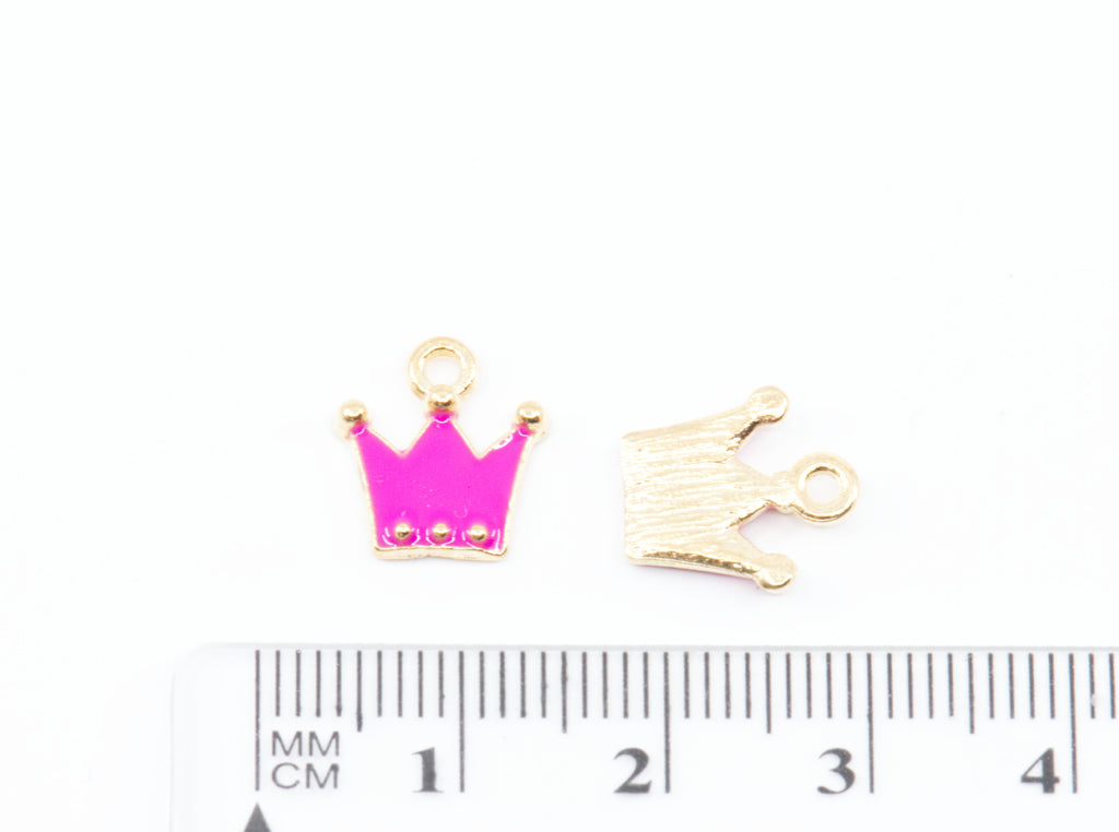 Two small crown-shaped jewelry charms shown above a ruler for scale on a white background.