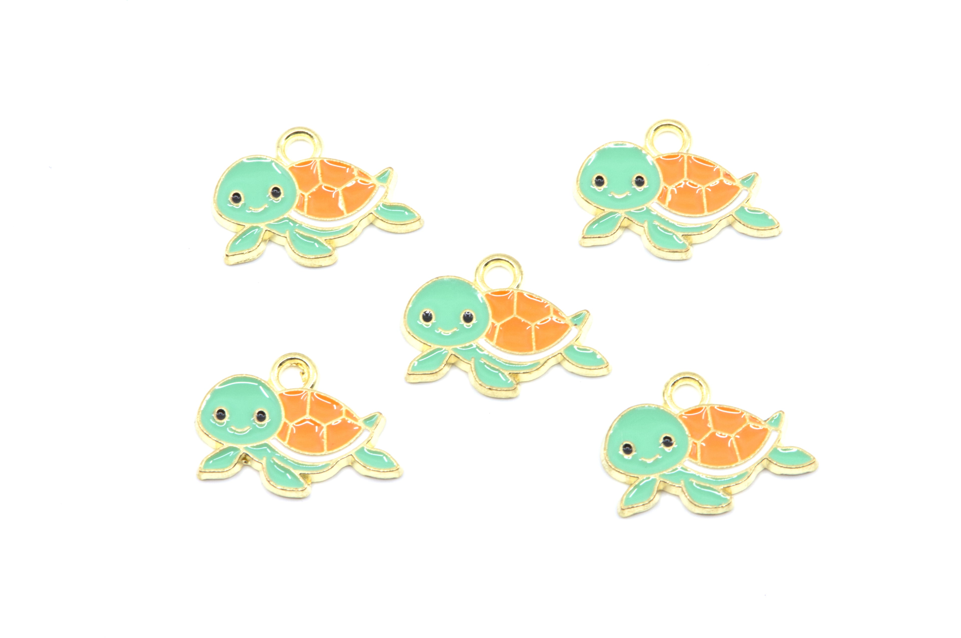 Five small turtle charms with mint green heads and flippers, orange shells, and gold-tone outlines on a plain white background.