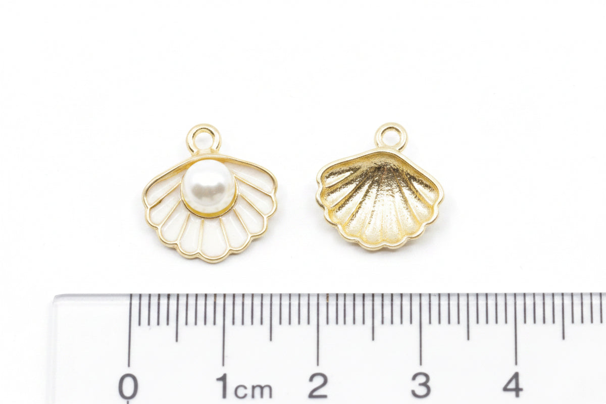 Two small shell-shaped jewelry charms shown on a white background with a ruler at the bottom for scale. 