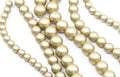 multiple strands of shiny shimmery gold acrylic beads shown on a white background 