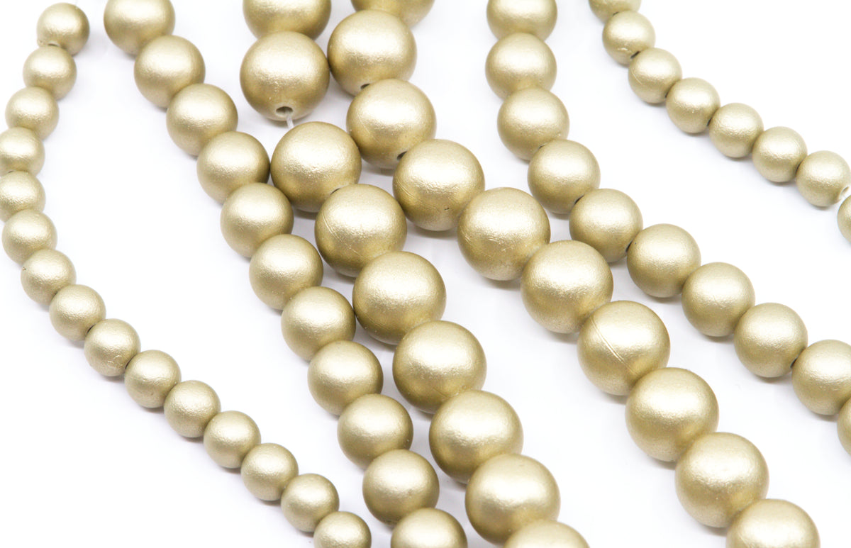 multiple strands of shiny shimmery gold acrylic beads shown on a white background 