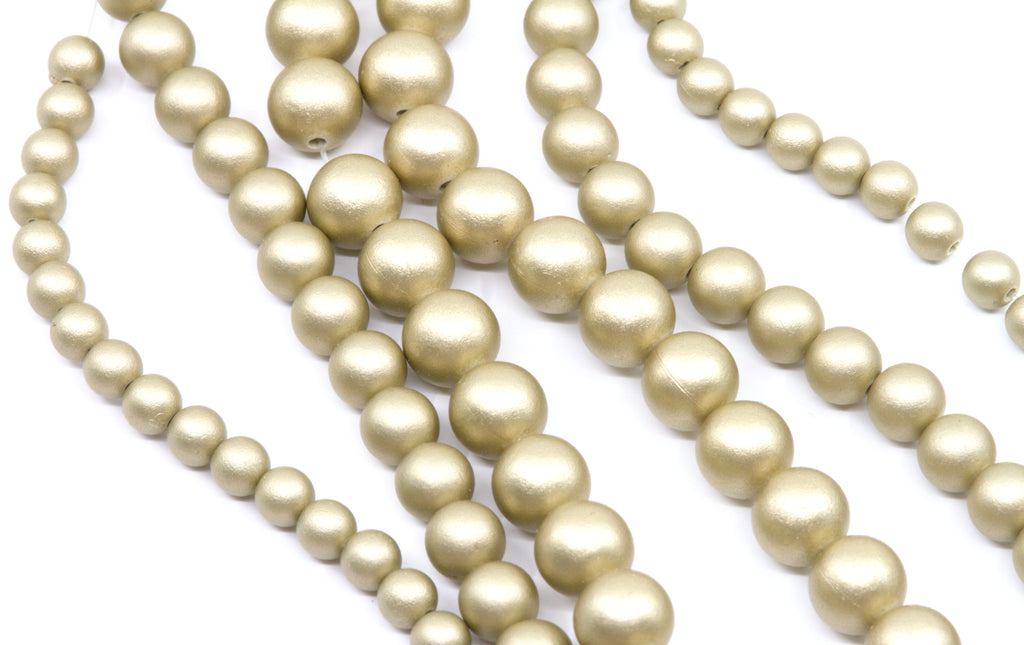 multiple strands of shiny shimmery gold acrylic beads shown on a white background 
