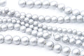 Multiple strands of silver shimmery acrylic beads in various sizes, arranged diagonally on a clean white background.