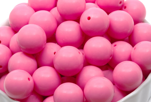 pink beads in a white bowl on a white background 