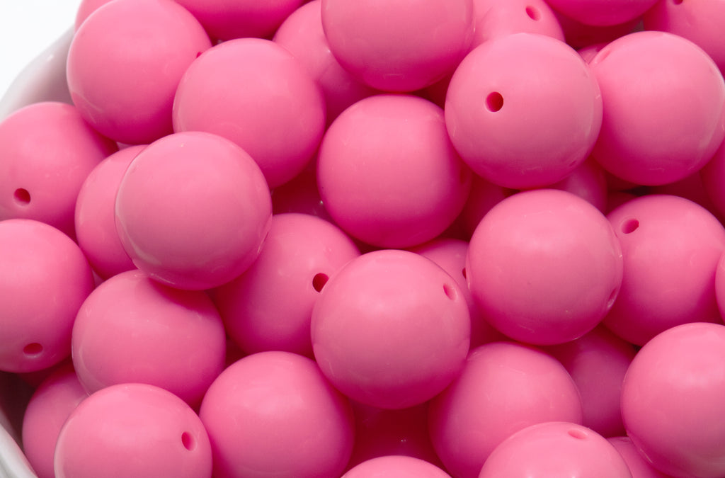 pink beads in a white bowl on a white background