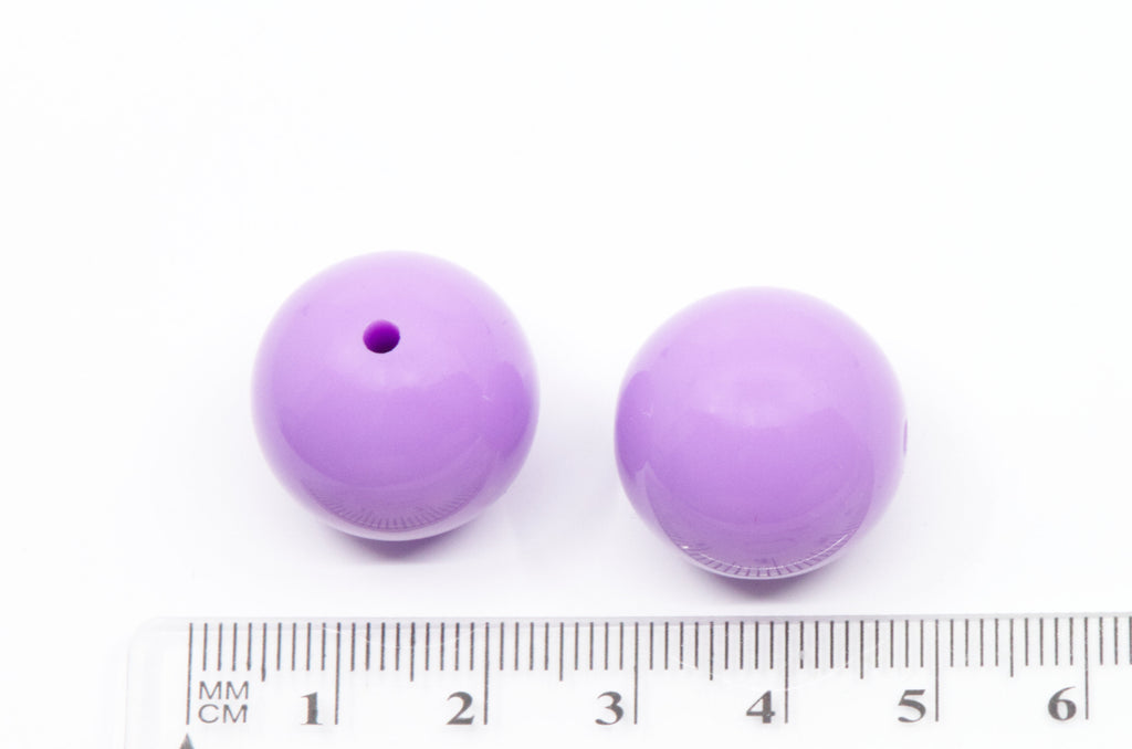 Two purple round beads with a ruler for scale on a white background