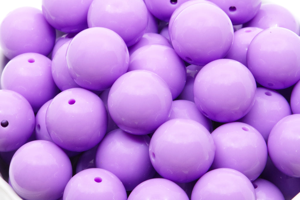 purple beads in a white bowl on a white background 