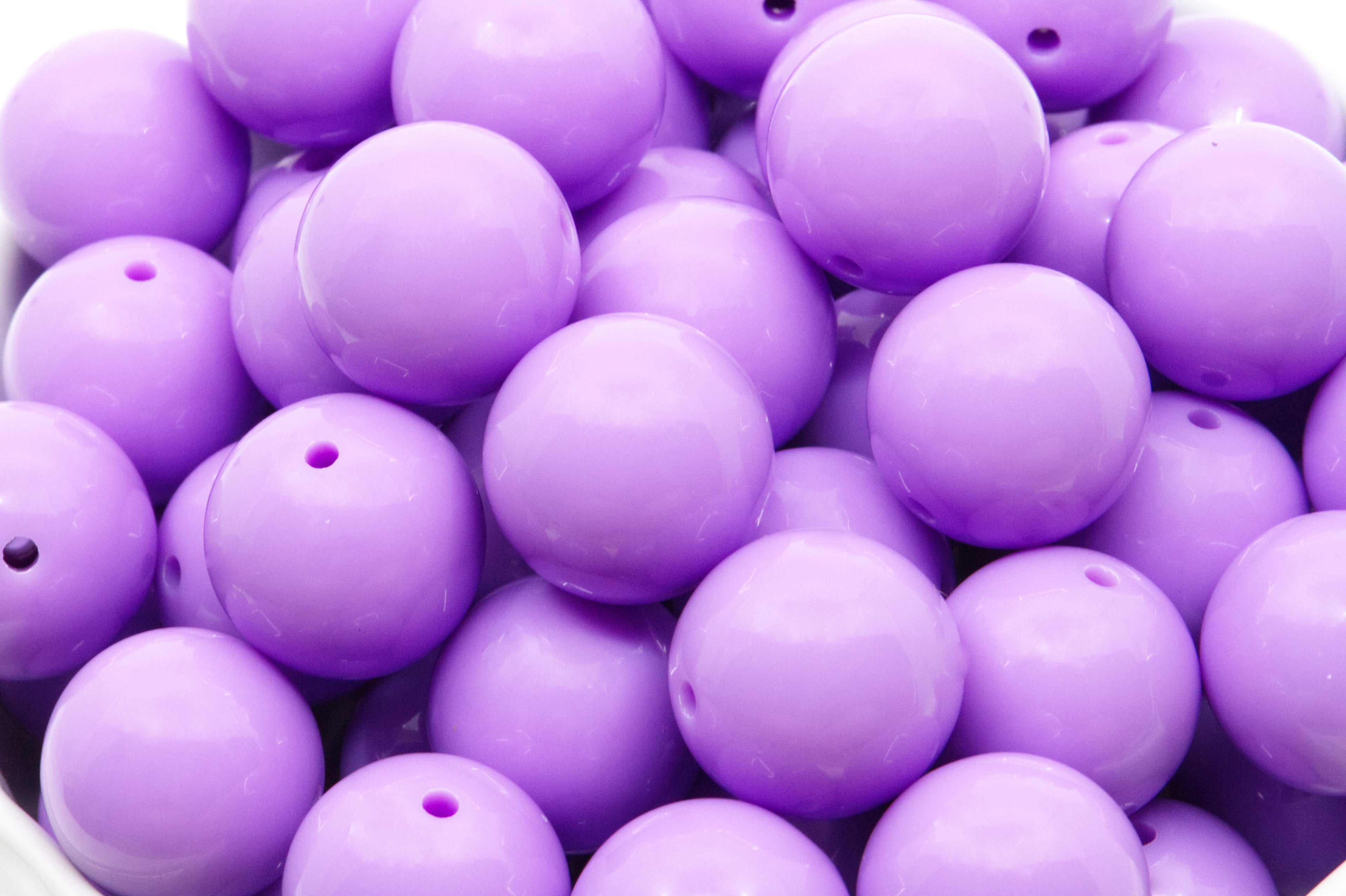 purple beads in a white bowl on a white background 