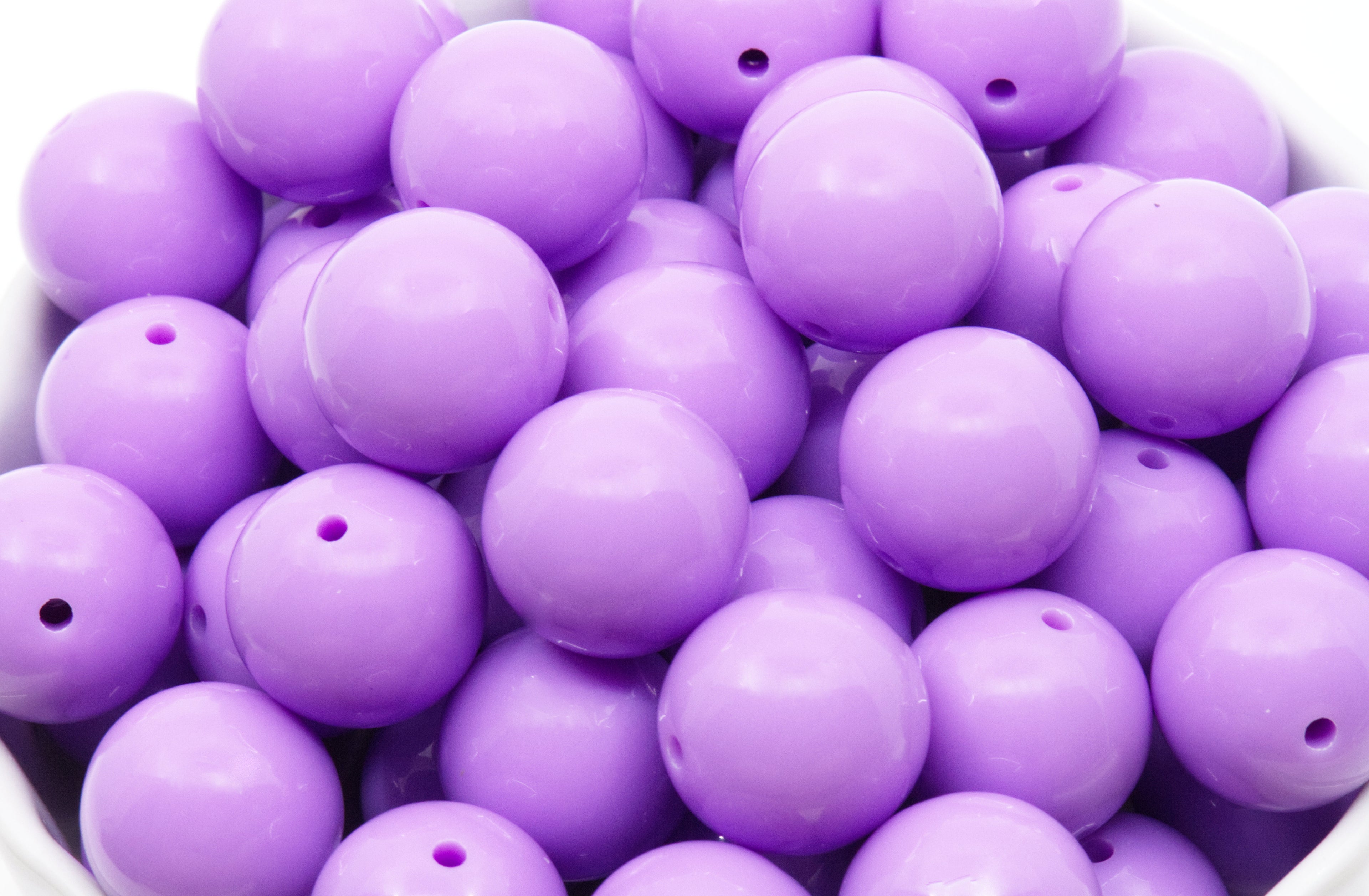 purple beads in a white bowl on a white background