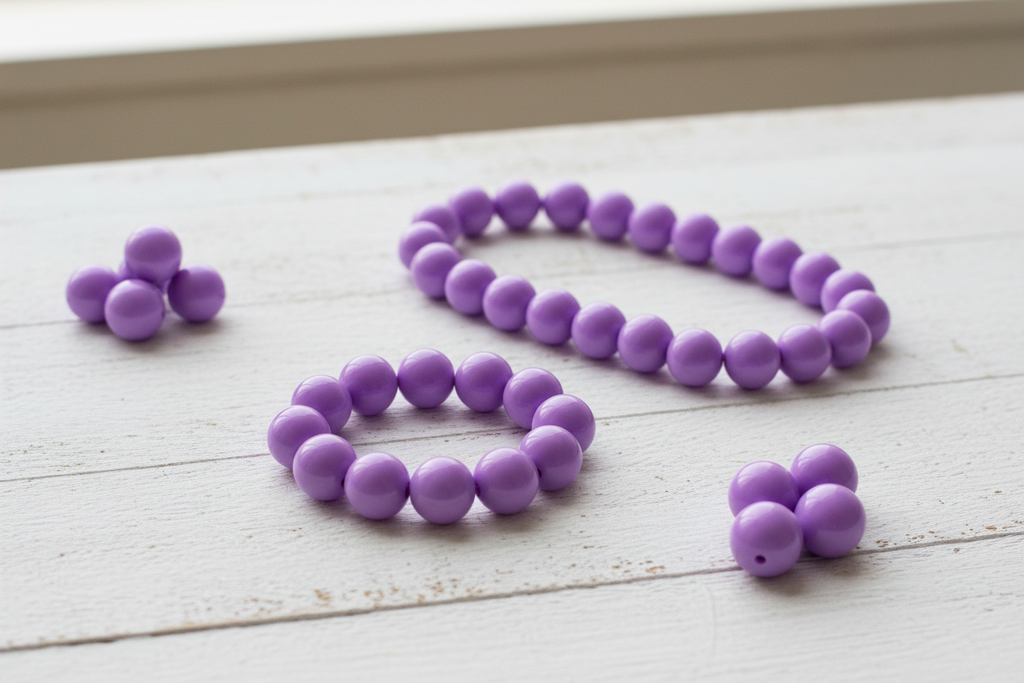 Purple beads shown as beaded necklace and bracelets on a light wooden surface