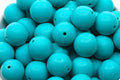 Close-up of blue beads in a white bowl on a white background