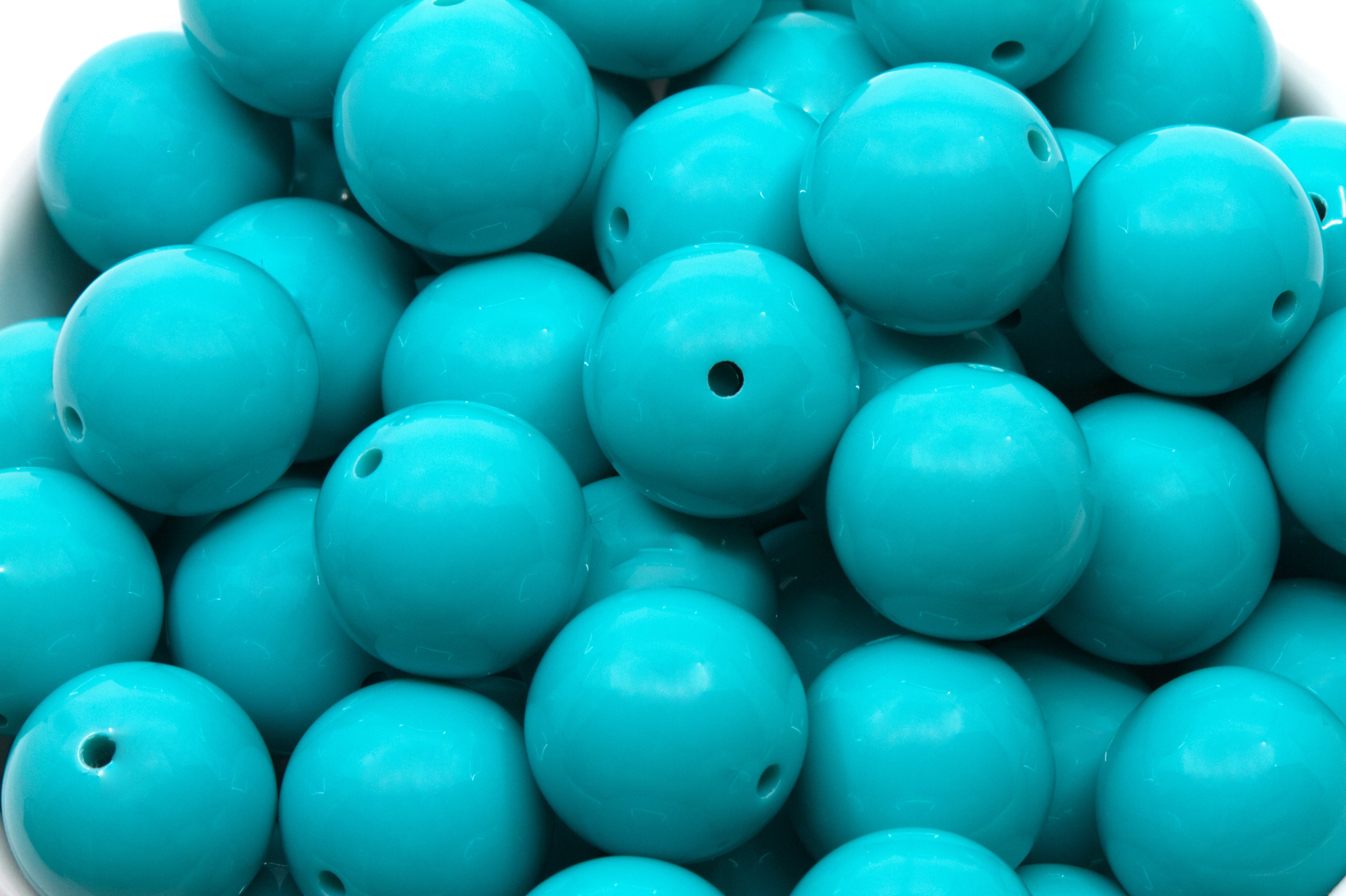 Close-up of blue beads in a white bowl on a white background