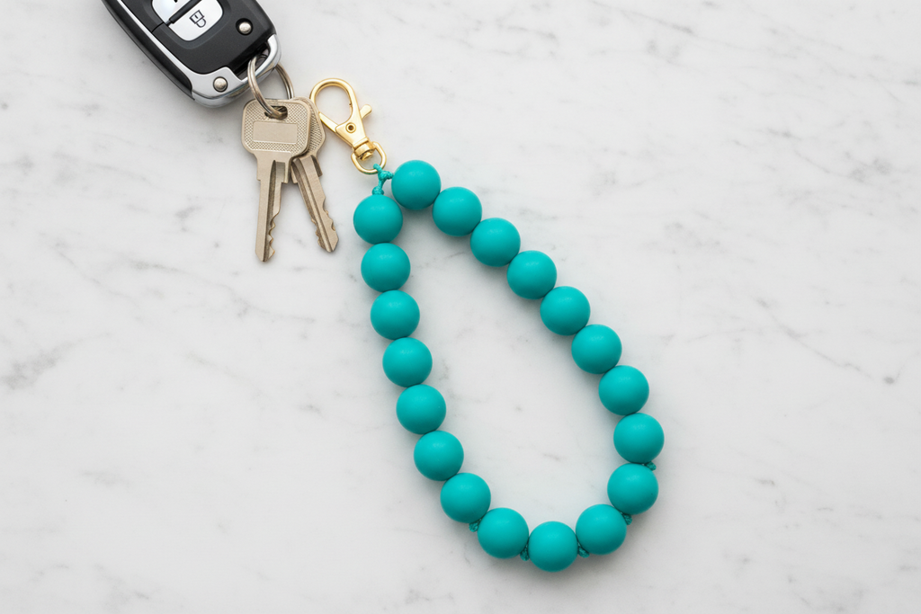 teal beads shown as a beaded keychain attached to keys on a marble surface