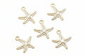 Five white and cream starfish-shaped jewelry charms arranged on a plain white background.