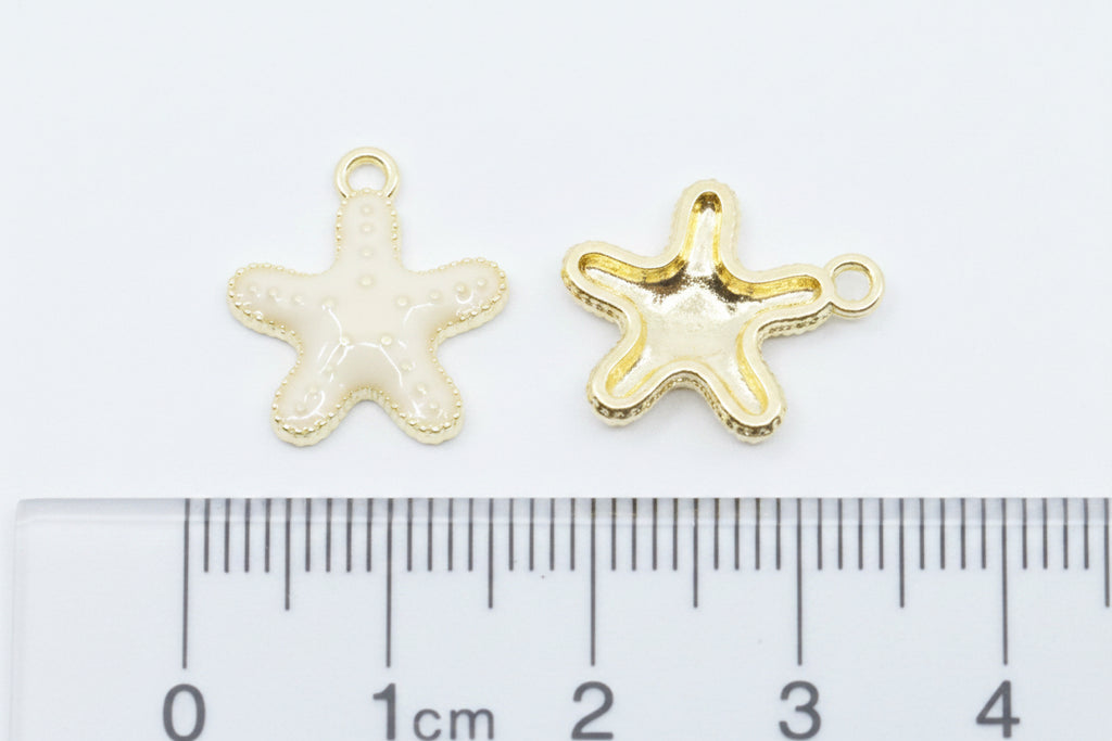 Two small starfish-shaped jewelry charms, displayed above a  cm ruler for scale on a white background.