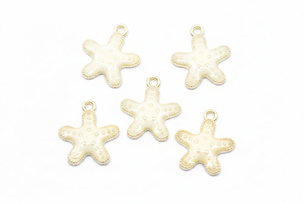 Five small starfish-shaped jewelry charms with cream enamel and gold-tone edges, arranged on a white background.