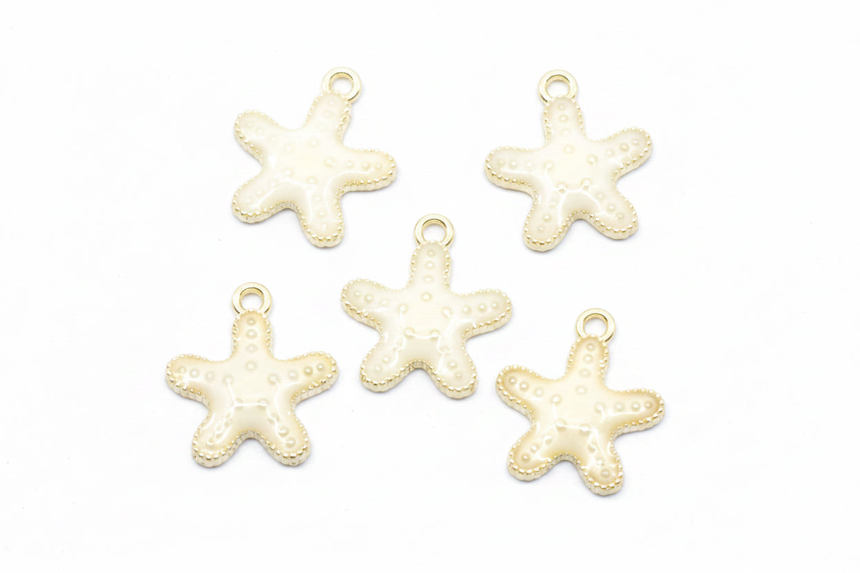 Five small starfish-shaped jewelry charms with cream enamel and gold-tone edges, arranged on a white background.