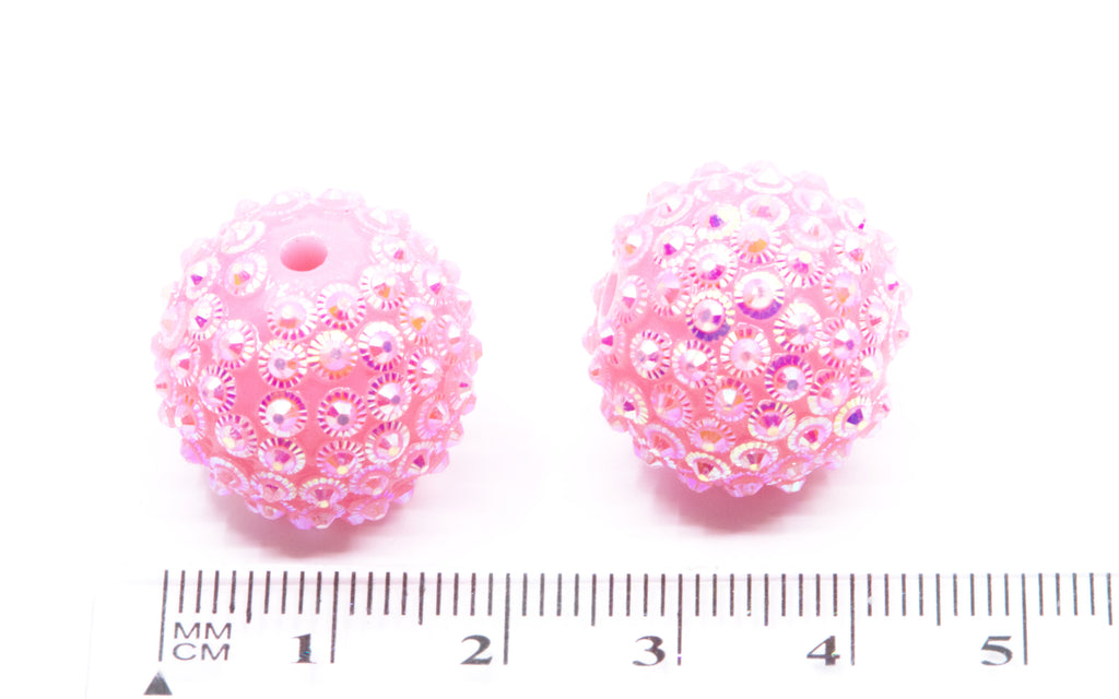 Two pink rhinestone bubblegum beads, shown next to a cm ruler for scale on a white background.