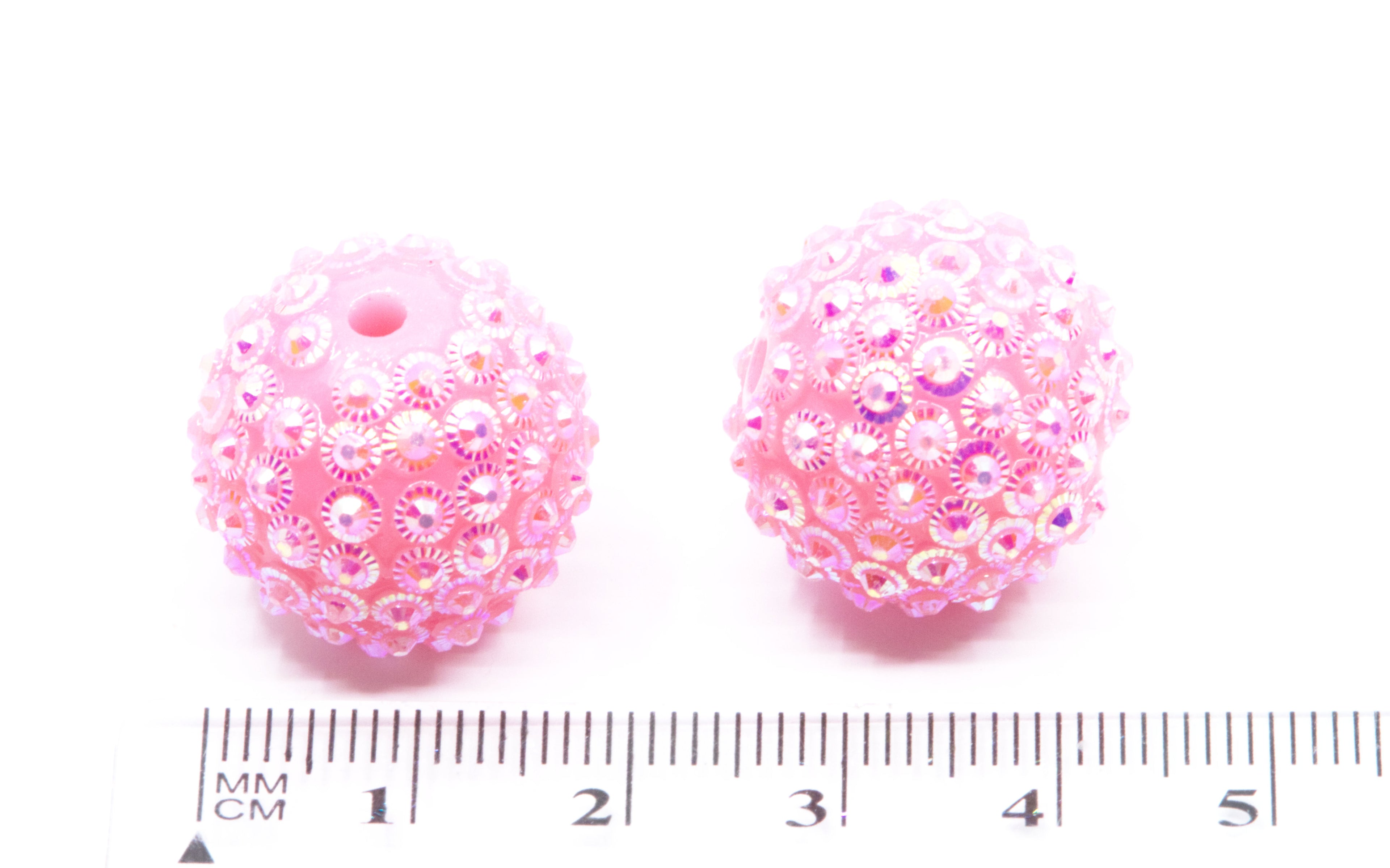 Two pink rhinestone bubblegum beads, shown next to a cm ruler for scale on a white background.