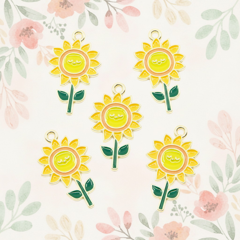 Five yellow sunflower charms with green stems and gold-tone loops, arranged on a light cream background with a soft floral pattern.