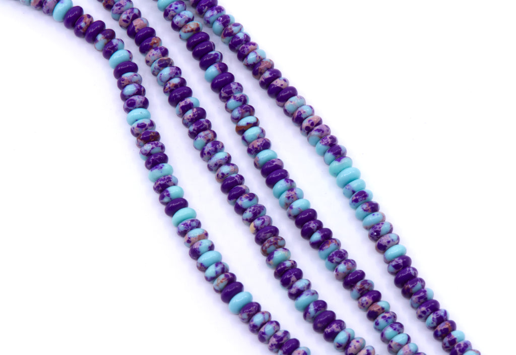 Four strands of rondelle synthetic purple jasper beads displayed diagonally on a white background