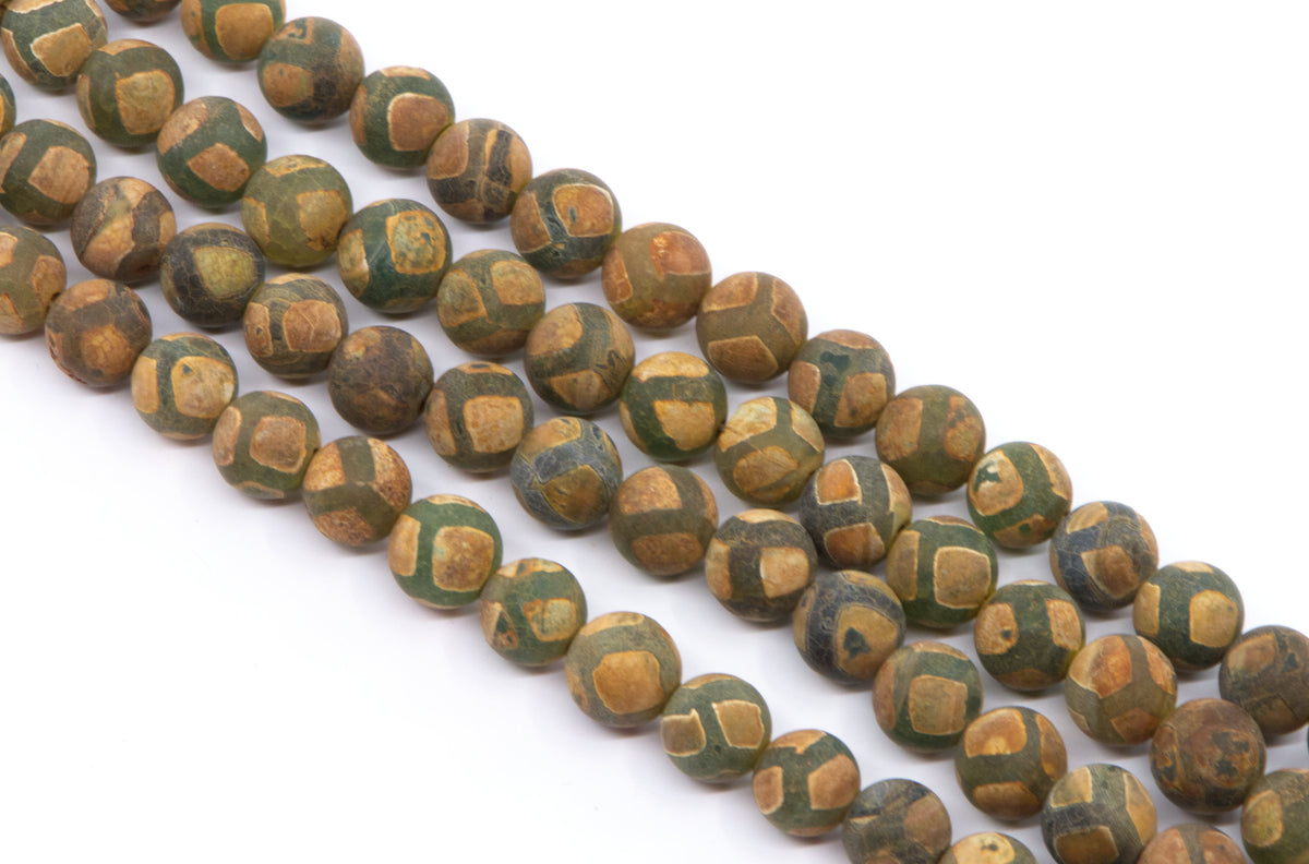 A close-up of multiple strands of round Tibetan agate beads in brown and green with a frosted surface , arranged diagonally on a plain white background.