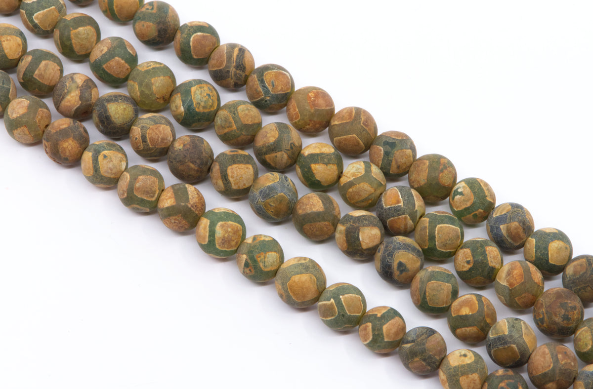A close-up of multiple strands of round Tibetan agate beads in brown and green with a frosted surface , arranged diagonally on a plain white background.