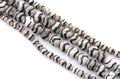 Four strands of round zebra striped beads with black and off-white stripes, arranged diagonally on a white background.