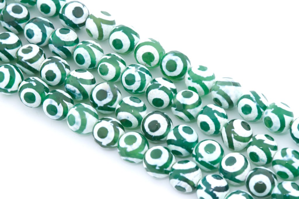 Green and white Tibetan agate  beads with a circular eye motif, arranged diagonally on a white background.