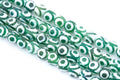 Green and white Tibetan agate  beads with a circular eye motif, arranged diagonally on a white background.