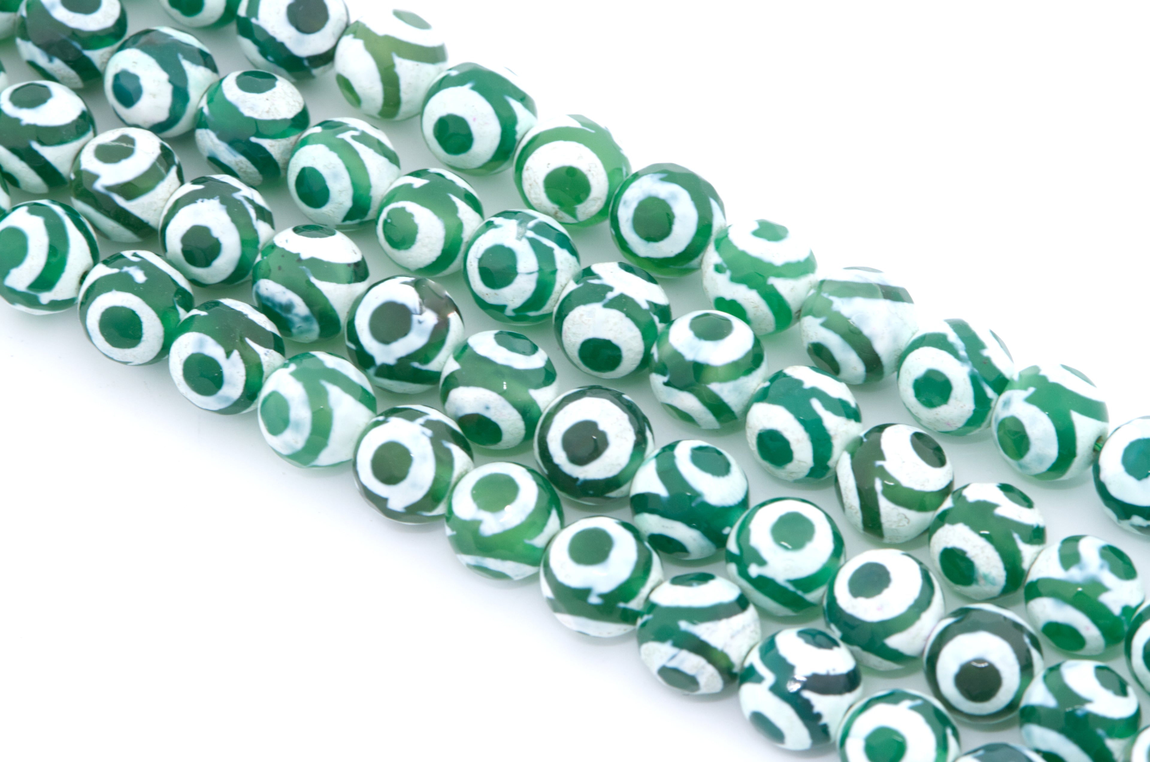 Green and white Tibetan agate  beads with a circular eye motif, arranged diagonally on a white background.