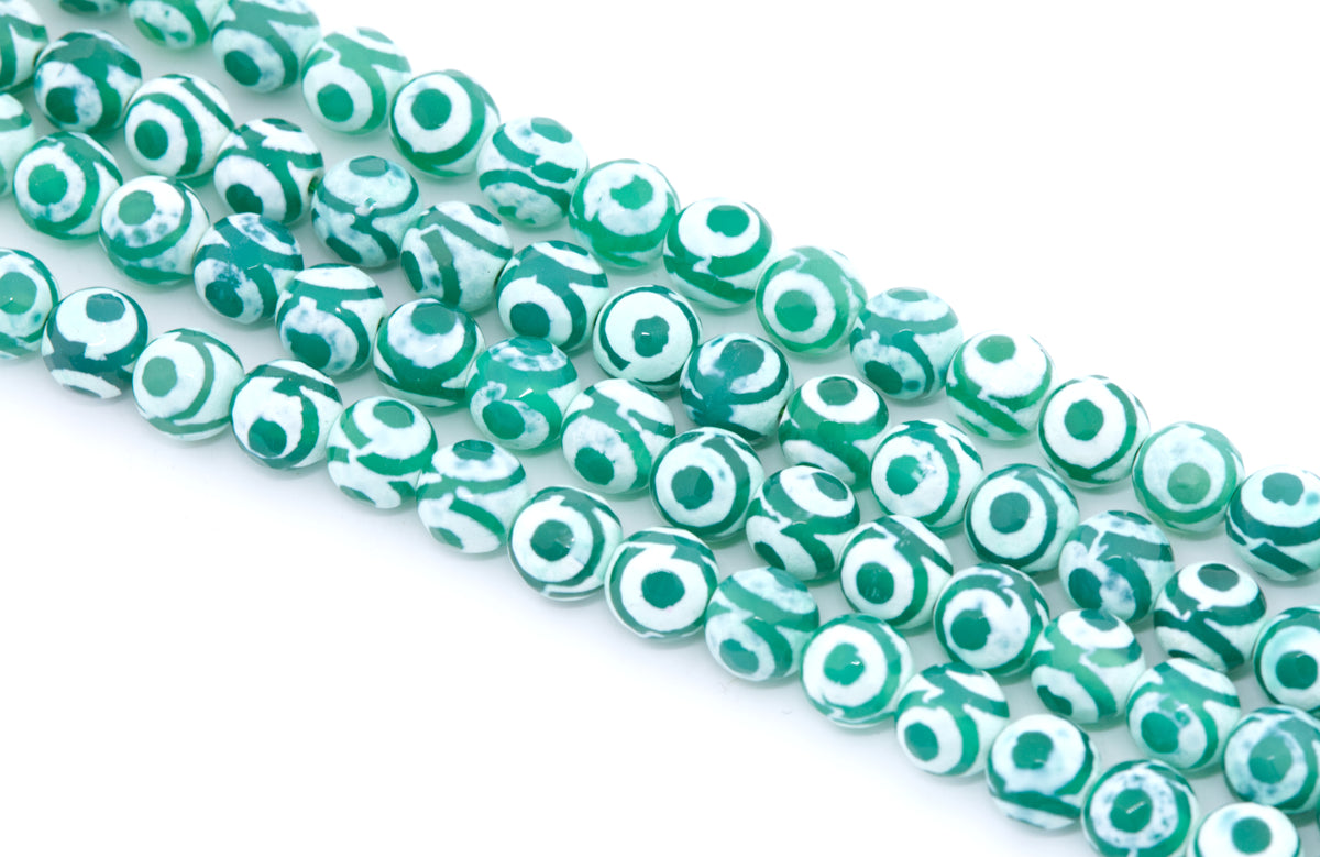 Green and white striped Tibetan agate beads with a circular eye motif, arranged in diagonal strands on a white background.