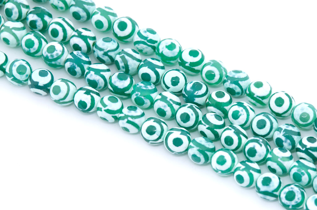 Green and white striped Tibetan agate beads with a circular eye motif, arranged in diagonal strands on a white background.