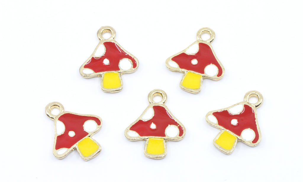 Five small mushroom-shaped charms with red and white spotted caps and yellow stems, outlined in gold-tone metal, arranged on a plain white background.