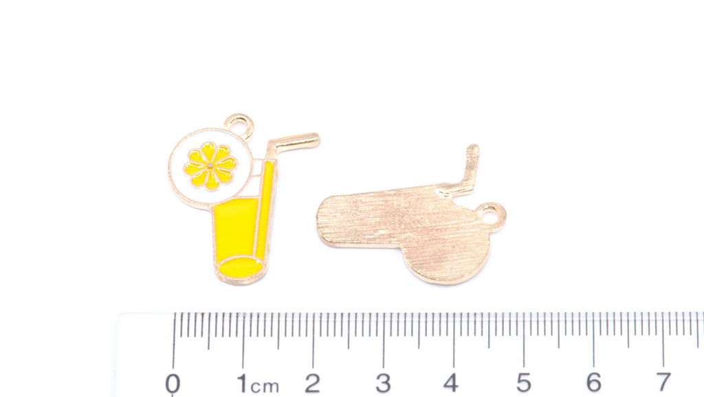 Two small enamel charms on a white background with a cm ruler at the bottom for scale. One charm depicts a yellow drink with a straw and garnish, and the other shows the back of a matching charm in a brushed gold-tone finish.